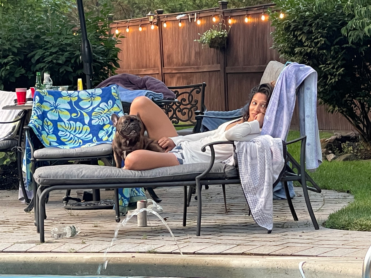 a picture of cris laying by the pool with a dog